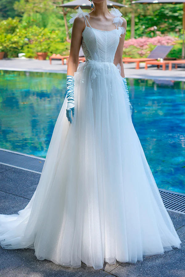 Un semplice abito da sposa con spalline sottili, perline a cucchiaio e un singolo filo